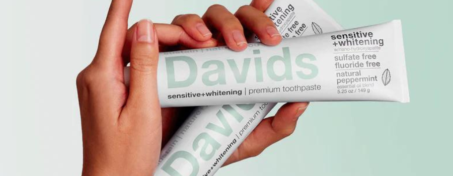 A hand holding a two tubes of Davids Sensitive+Whitening Hydroxyapatite Toothpaste